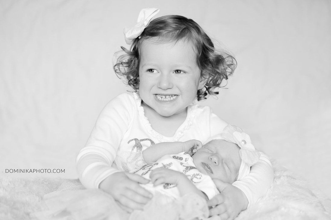 sister holding newborn at home, newborn photography milwaukee
